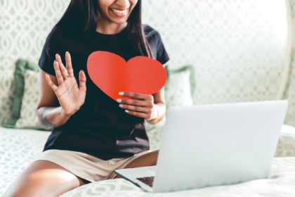 A woman happily chatting with lover, holding a heart, love during COVID, long distance relationship