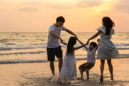 Asian young happy family enjoy vacation on beach in the evening.