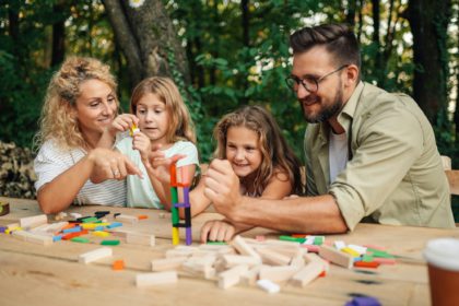 Family is having fun with wood block puzzle game in nature.