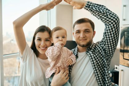 Small child in the arms of parents in bright kitchen