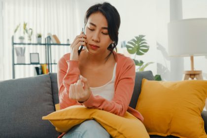 Young lady sitting on sofa talk with friend and get bad news at home. Long distance relationship.