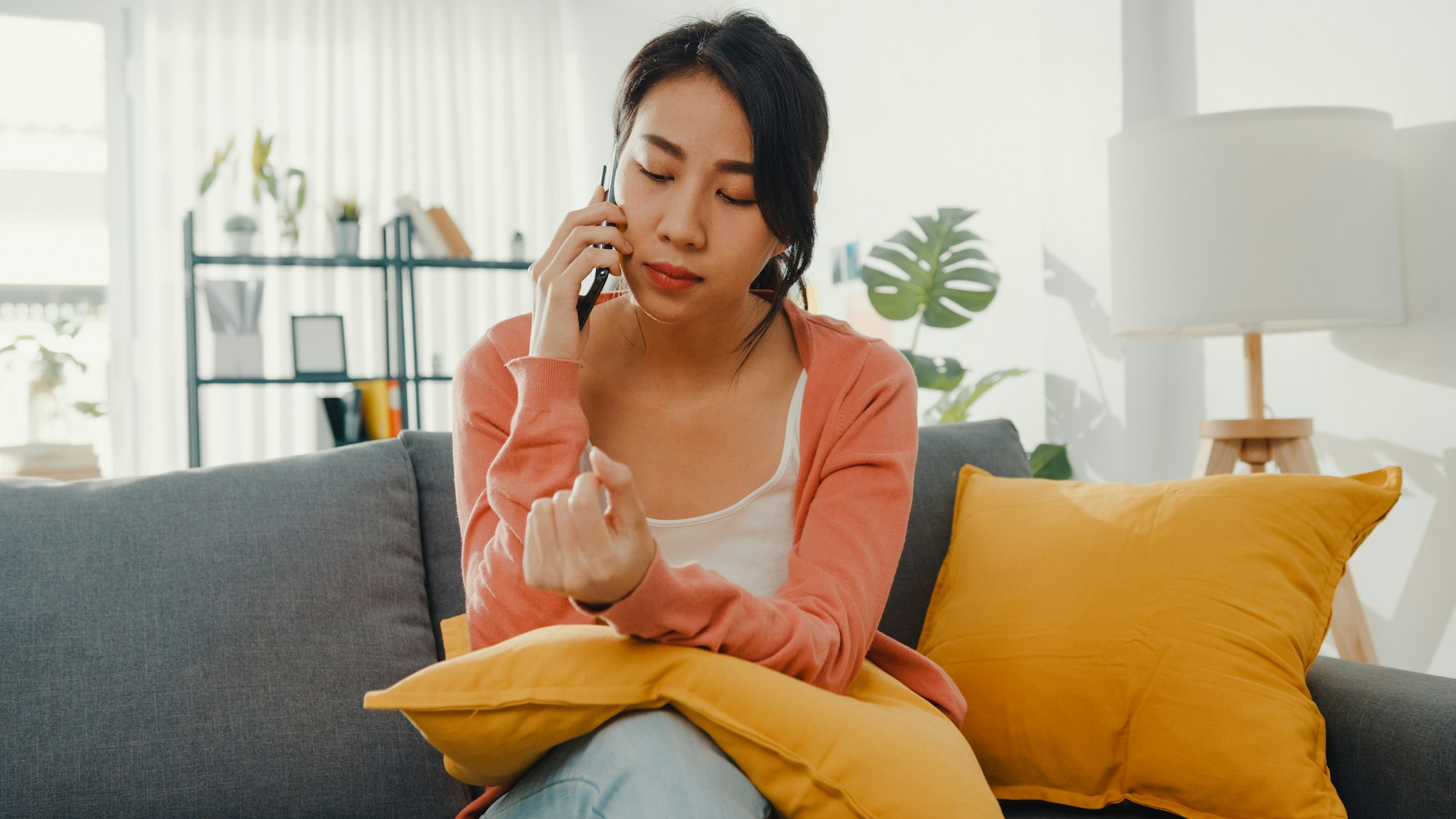 Young lady sitting on sofa talk with friend and get bad news at home. Long distance relationship.